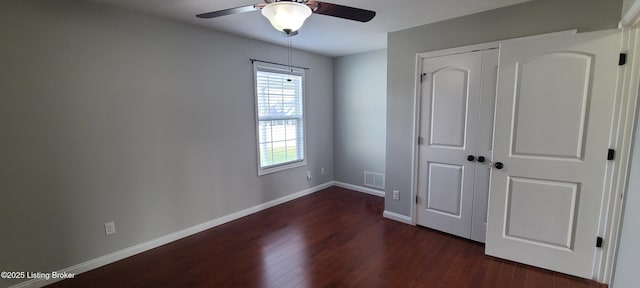 unfurnished bedroom featuring baseboards, visible vents, dark wood-style flooring, ceiling fan, and a closet