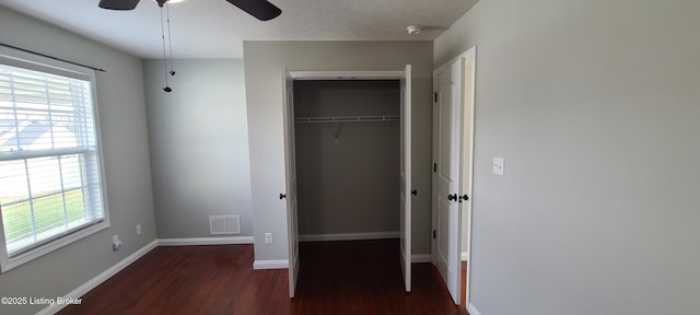 unfurnished bedroom with a closet, visible vents, multiple windows, and wood finished floors