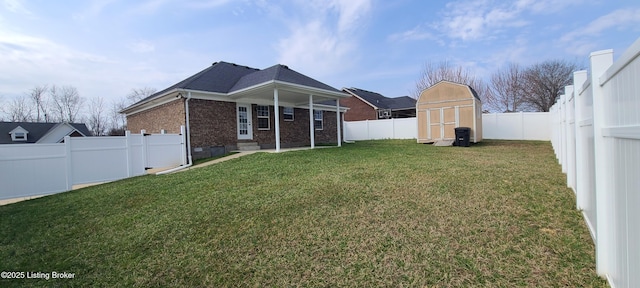 view of yard with a storage shed, an outbuilding, and a fenced backyard