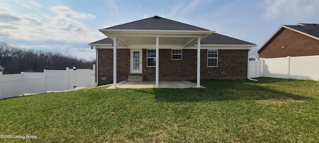 back of house featuring a yard, brick siding, and a fenced backyard