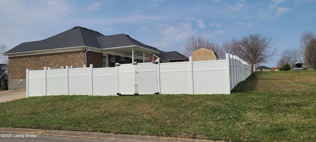 view of side of home with brick siding, a yard, and fence