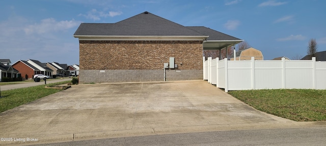 view of home's exterior featuring brick siding, roof with shingles, and fence