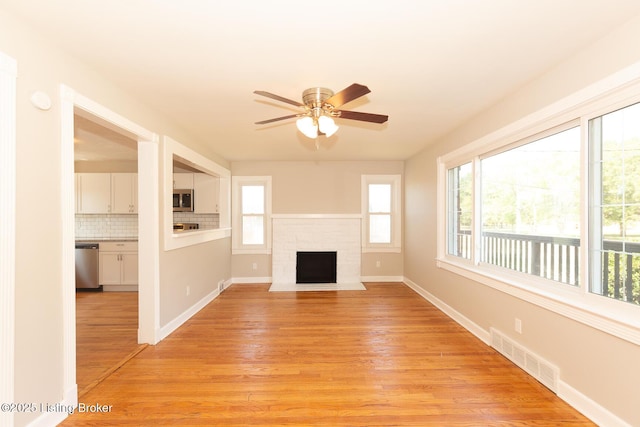 unfurnished living room with ceiling fan, visible vents, baseboards, and light wood-style flooring