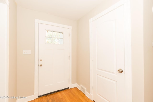 foyer entrance with light wood-type flooring, baseboards, and visible vents