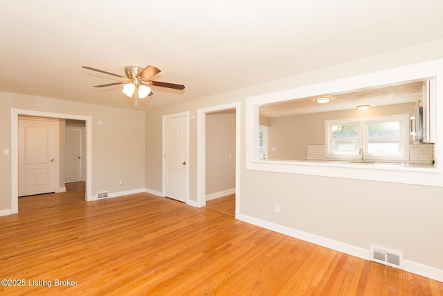 empty room with baseboards, visible vents, light wood finished floors, and ceiling fan