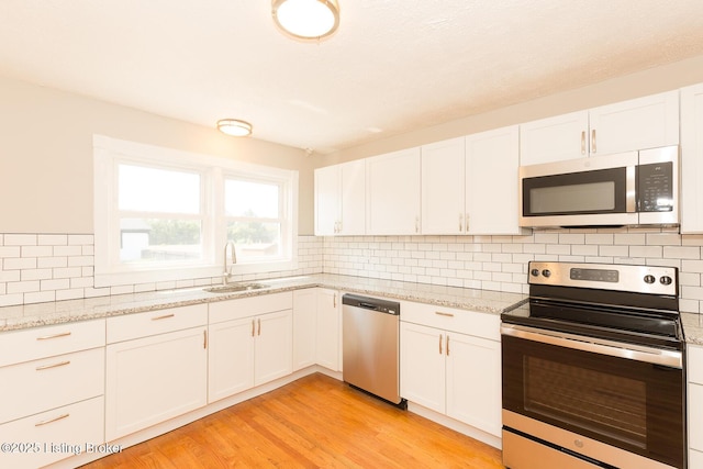 kitchen featuring a sink, light wood-style floors, tasteful backsplash, and stainless steel appliances