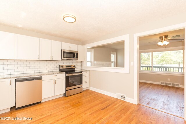 kitchen featuring decorative backsplash, visible vents, white cabinetry, and stainless steel appliances