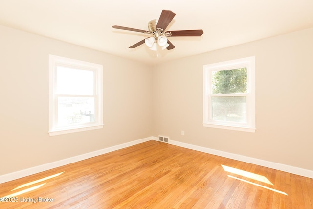 spare room featuring ceiling fan, visible vents, baseboards, and wood finished floors