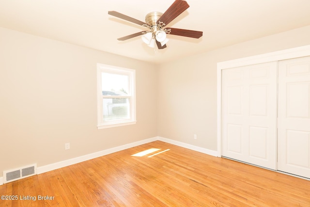 unfurnished bedroom featuring light wood finished floors, visible vents, ceiling fan, baseboards, and a closet