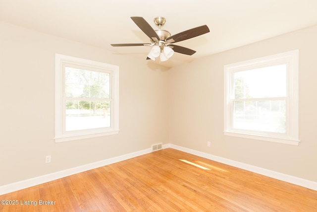 spare room with visible vents, a ceiling fan, light wood-style floors, and baseboards