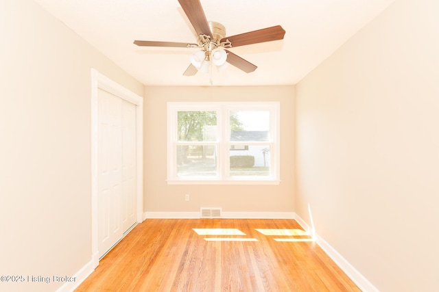 unfurnished room featuring a ceiling fan, light wood-style flooring, baseboards, and visible vents