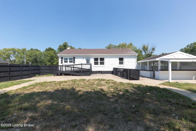 back of house featuring a yard, a deck, and a fenced backyard