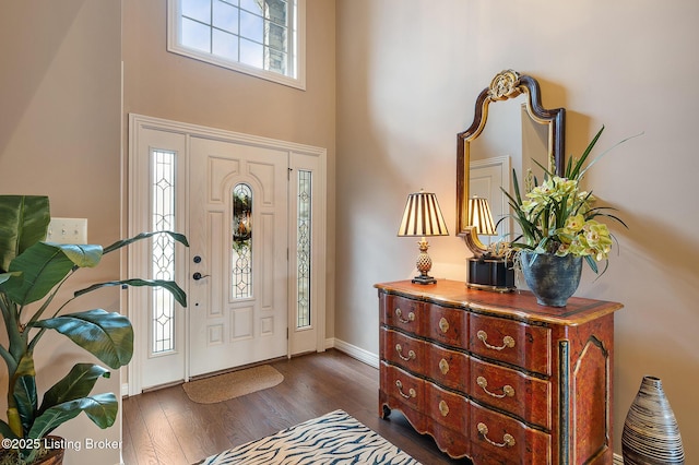 entrance foyer featuring dark wood-type flooring, baseboards, and a towering ceiling