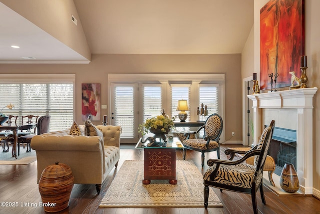 living area featuring visible vents, baseboards, wood finished floors, and a tile fireplace