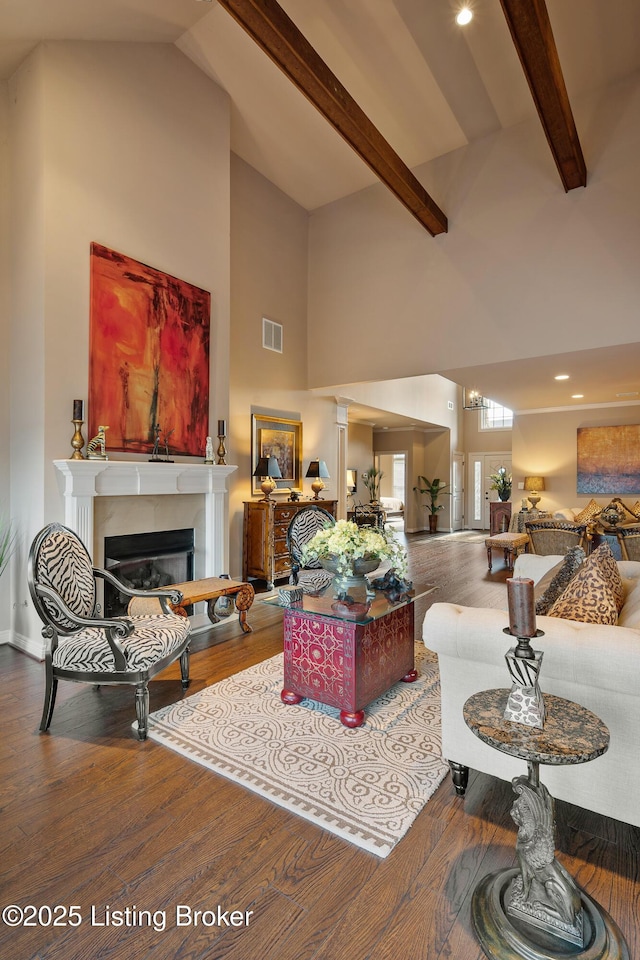 living room with visible vents, beamed ceiling, wood finished floors, a glass covered fireplace, and high vaulted ceiling