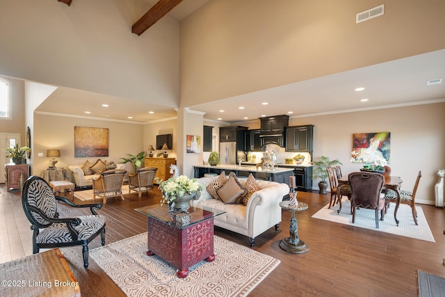 living area featuring visible vents, wood finished floors, recessed lighting, a high ceiling, and crown molding