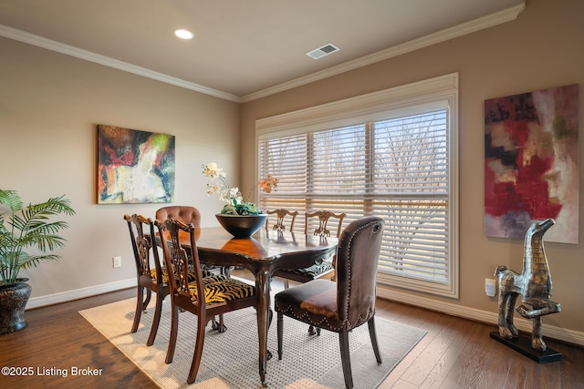 dining area with baseboards, hardwood / wood-style floors, and crown molding