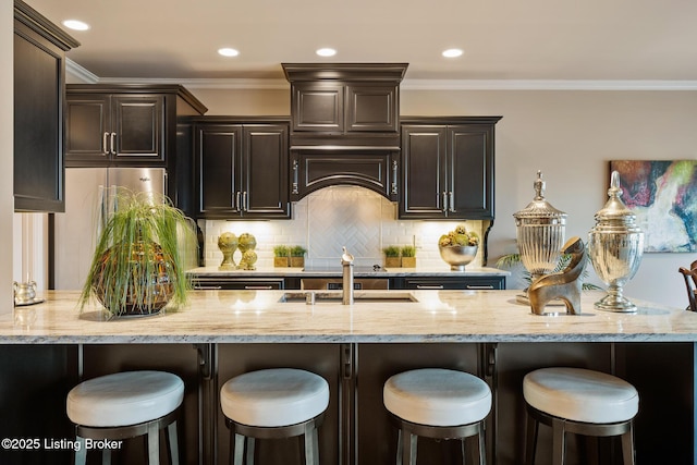 kitchen featuring a breakfast bar, light stone countertops, tasteful backsplash, and ornamental molding