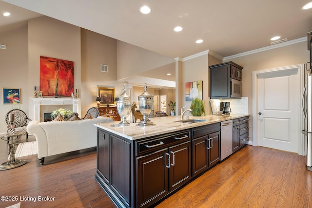 kitchen with visible vents, a sink, open floor plan, a peninsula, and light stone countertops