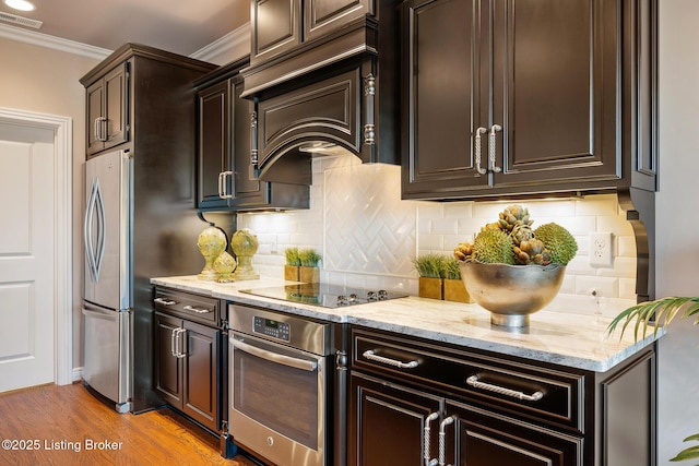 kitchen with visible vents, custom range hood, appliances with stainless steel finishes, crown molding, and light wood finished floors