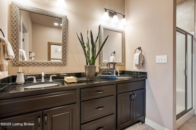 bathroom with a sink, baseboards, a stall shower, and double vanity