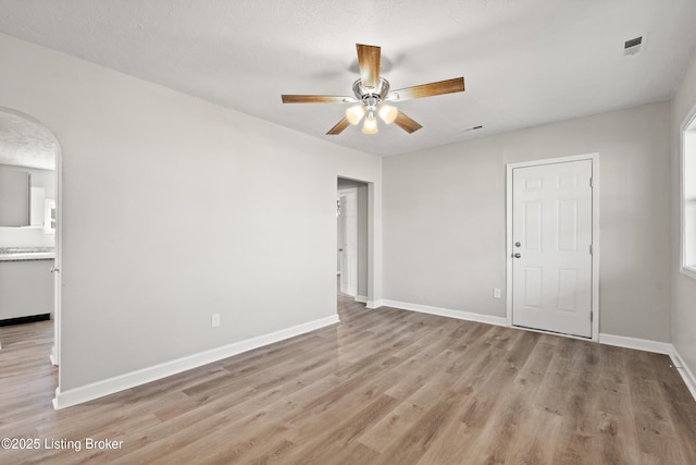 interior space with light wood-type flooring, baseboards, visible vents, and a ceiling fan