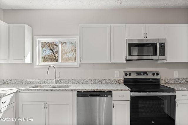 kitchen featuring a sink, a textured ceiling, white cabinets, and stainless steel appliances