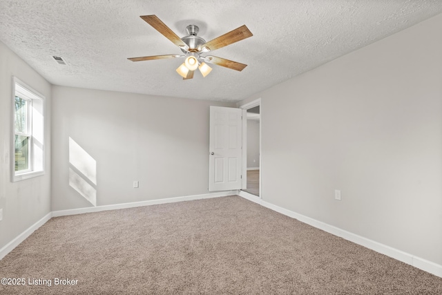 empty room featuring a ceiling fan, carpet, visible vents, baseboards, and a textured ceiling