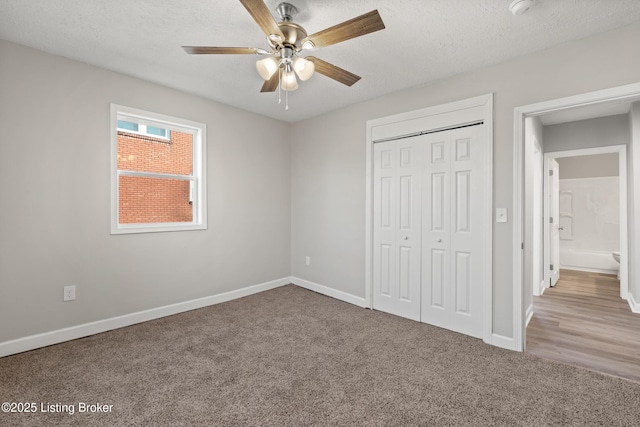 unfurnished bedroom with a closet, carpet flooring, a textured ceiling, and baseboards