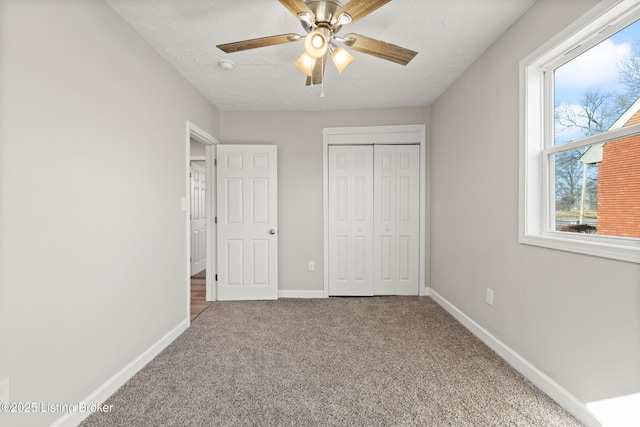 unfurnished bedroom with a closet, baseboards, ceiling fan, and carpet flooring