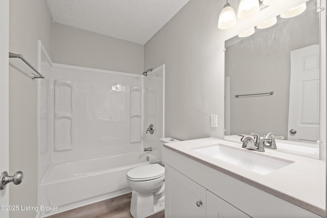 bathroom featuring toilet, a textured ceiling, wood finished floors, shower / bath combination, and vanity