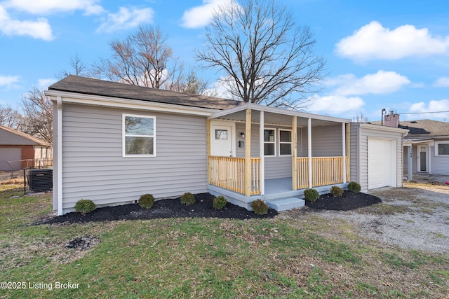 ranch-style home with covered porch, a front lawn, central AC, and a garage