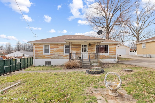 bungalow-style house with covered porch, concrete driveway, a front lawn, and fence