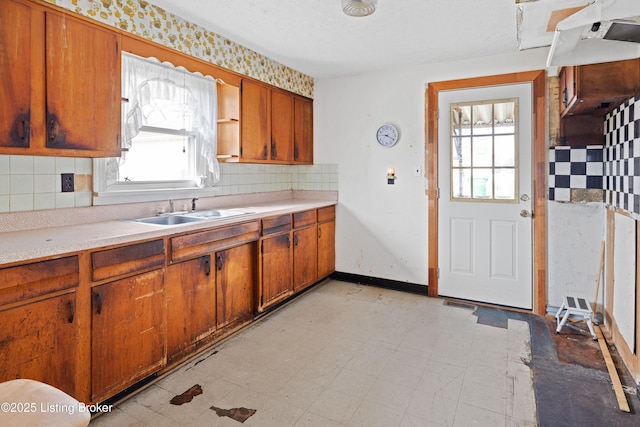 kitchen with brown cabinetry, light floors, light countertops, and a sink