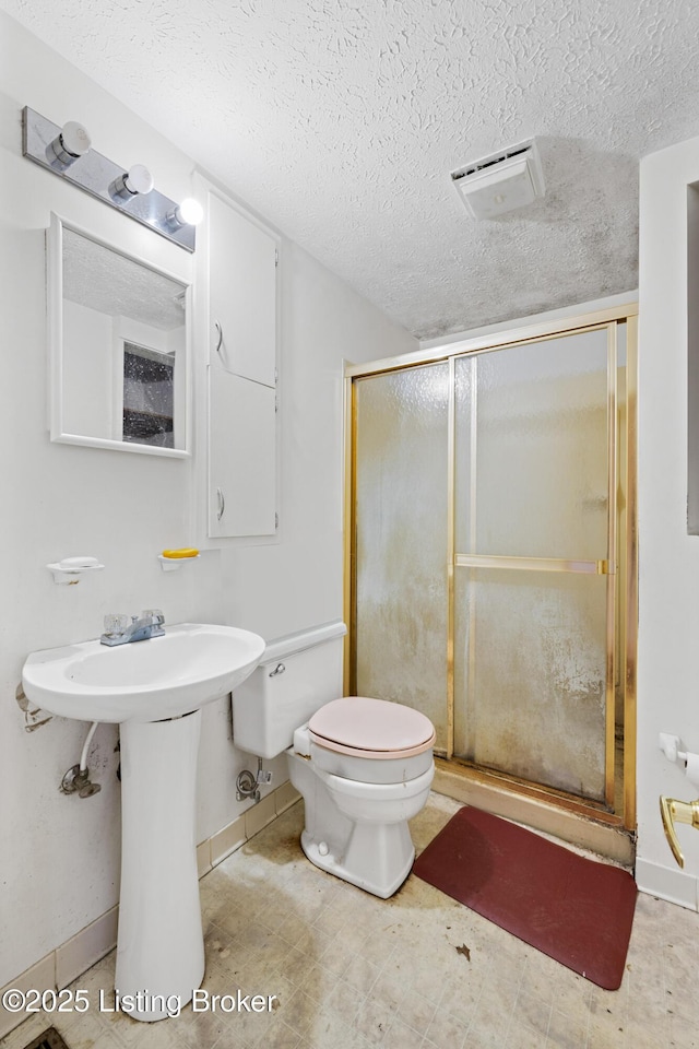 bathroom with baseboards, visible vents, a shower stall, a textured ceiling, and toilet