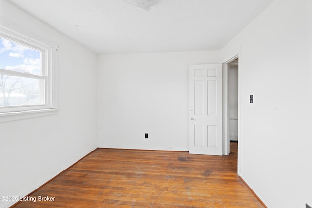 spare room with baseboards and hardwood / wood-style flooring