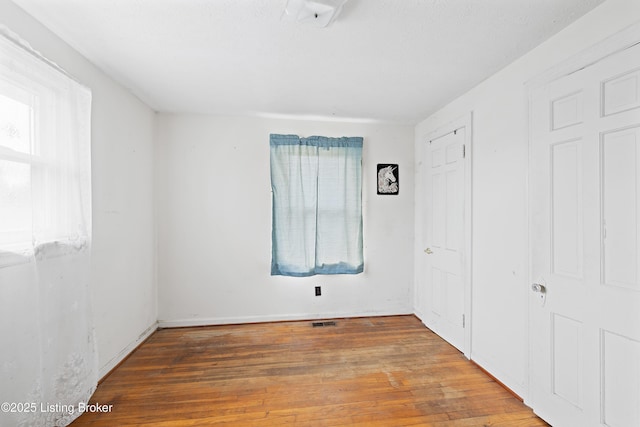 unfurnished bedroom featuring wood finished floors and visible vents