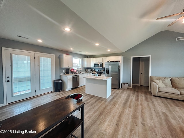 kitchen with visible vents, a sink, open floor plan, stainless steel appliances, and white cabinets