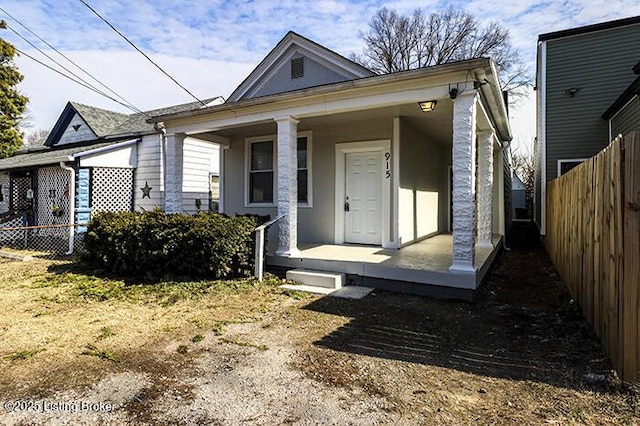 shotgun-style home with a porch and fence