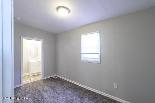 unfurnished bedroom featuring baseboards, carpet floors, and ensuite bath