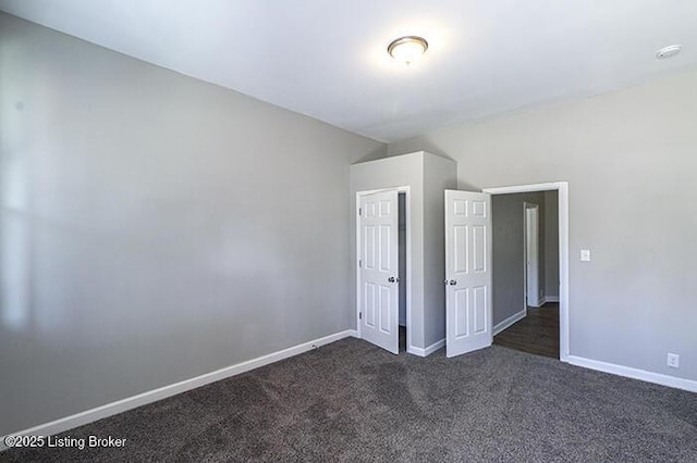 unfurnished bedroom featuring dark carpet and baseboards