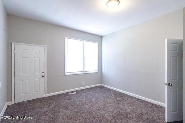 spare room featuring baseboards and dark colored carpet