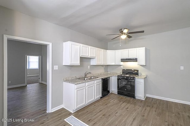 kitchen featuring black appliances, a ceiling fan, a sink, white cabinetry, and light wood-style floors