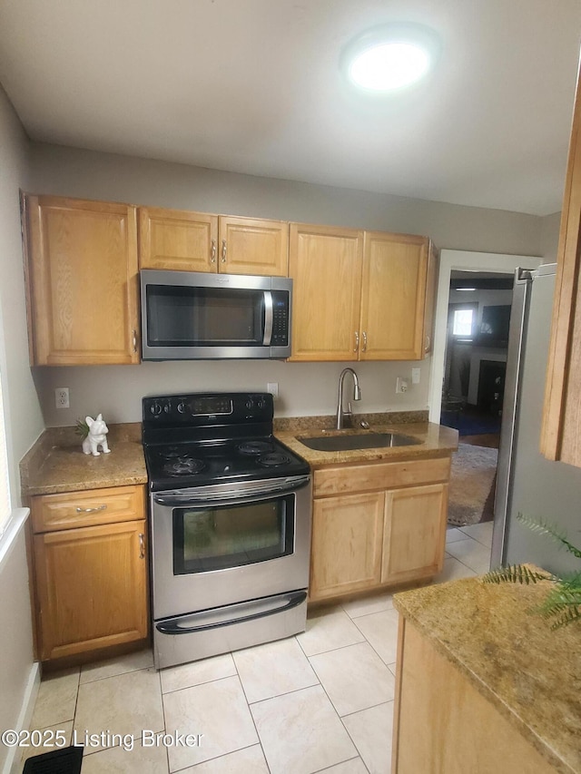 kitchen featuring a sink, appliances with stainless steel finishes, light tile patterned flooring, and light brown cabinetry