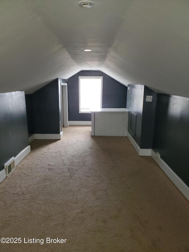 bonus room with visible vents, baseboards, light colored carpet, and vaulted ceiling