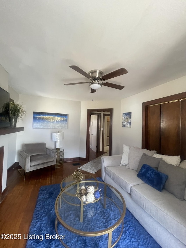 living room with baseboards, a ceiling fan, and wood finished floors