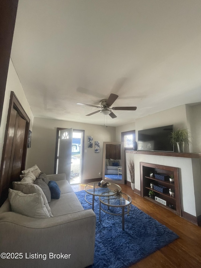 living area with a wealth of natural light, ceiling fan, and wood finished floors