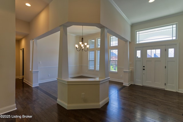 foyer entrance with dark wood-style floors, a chandelier, baseboards, ornamental molding, and a towering ceiling