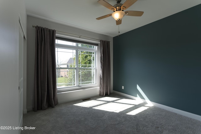 unfurnished room with carpet, visible vents, and baseboards