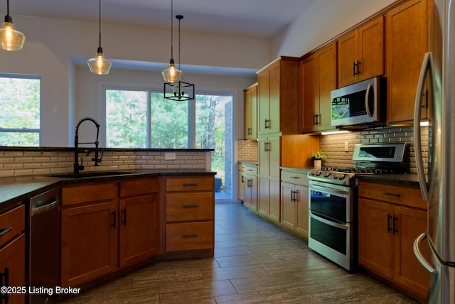 kitchen with brown cabinets, decorative backsplash, a sink, appliances with stainless steel finishes, and dark countertops